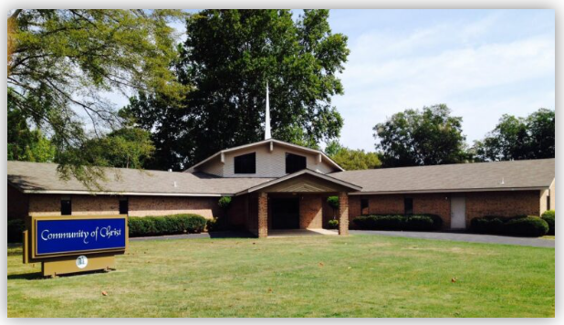 Community of Christ church building featuring a modern design, surrounded by greenery and a well-maintained lawn. The sign indicates its purpose.