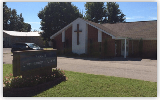 Bernie Community of Christ building with a prominent cross display. The sign in front identifies the church. Lush greenery enhances the welcoming atmosphere.
