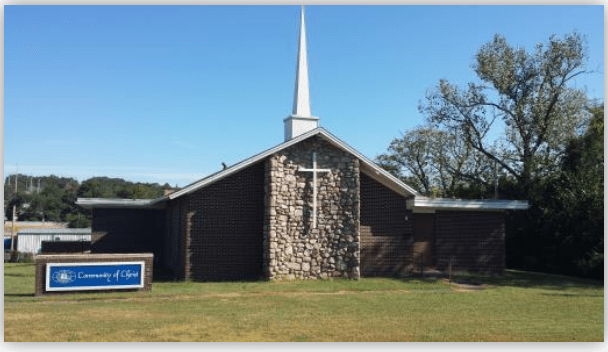 Community of Christ church with a prominent white steeple and stone facade, set against a clear blue sky and green lawn.