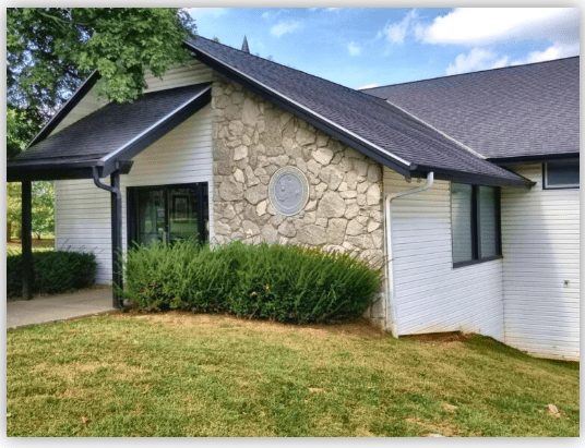 Community center exterior featuring a stone-accented wall, large windows, and landscaped greenery, illustrating a welcoming public space.