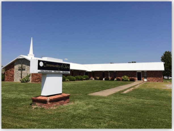 Community of Christ church building, featuring a white spire, manicured lawn, and an informative sign, highlights its welcoming environment for worship.